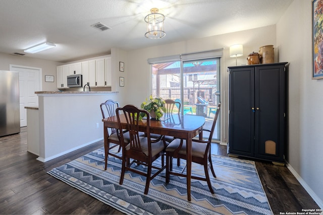 dining room featuring dark hardwood / wood-style flooring, a chandelier, and a textured ceiling