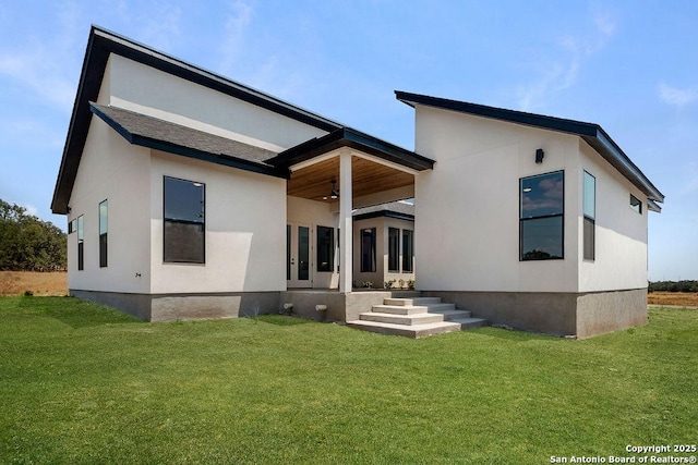 rear view of property featuring ceiling fan and a lawn