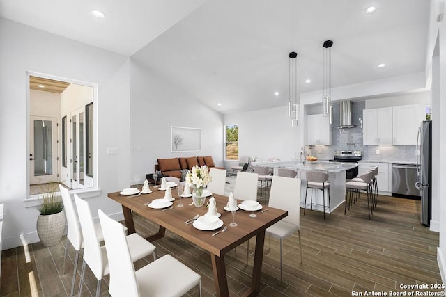 dining area featuring vaulted ceiling and dark hardwood / wood-style flooring