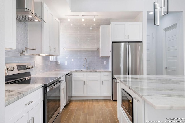 kitchen with appliances with stainless steel finishes, decorative light fixtures, sink, white cabinets, and light stone countertops