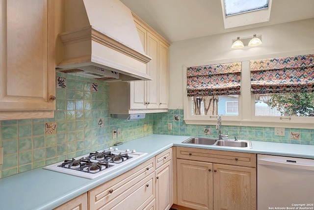 kitchen with sink, decorative backsplash, custom exhaust hood, light brown cabinets, and white appliances