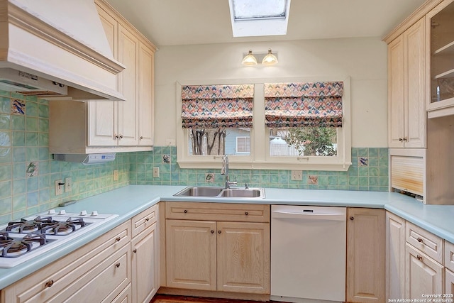 kitchen with sink, a skylight, custom range hood, white appliances, and decorative backsplash