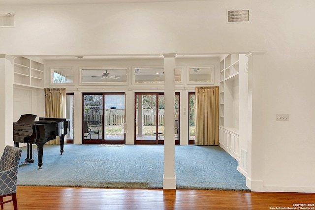 misc room featuring wood-type flooring, ceiling fan, and a high ceiling