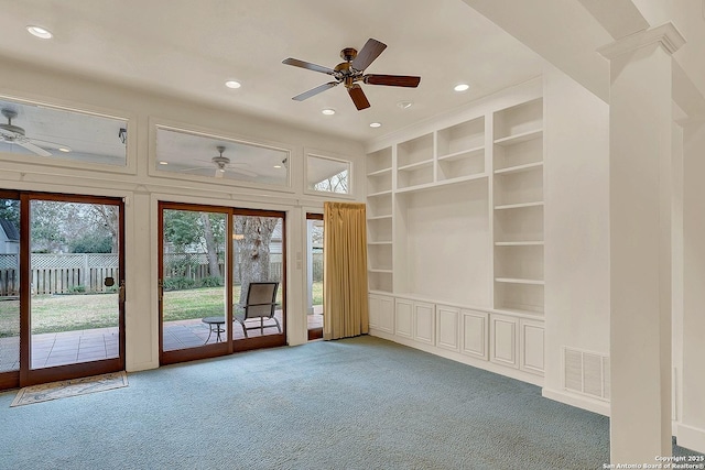 empty room with carpet floors, built in features, and ceiling fan