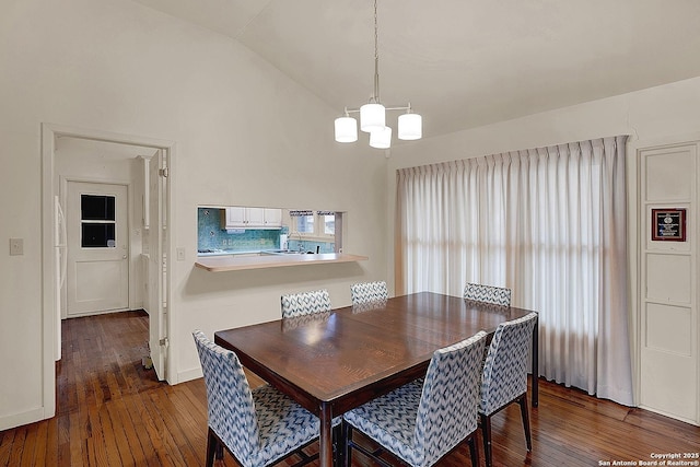 dining area with dark wood-type flooring, vaulted ceiling, and a notable chandelier