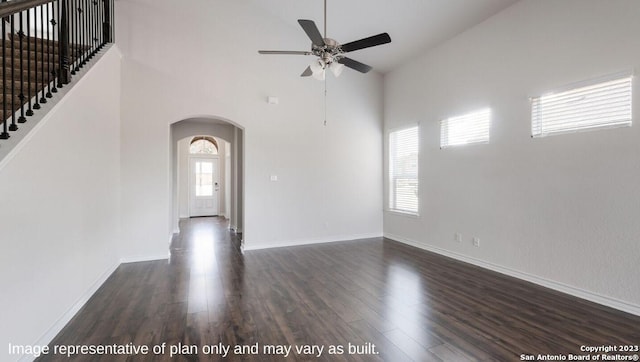 spare room with ceiling fan, a towering ceiling, and dark hardwood / wood-style flooring