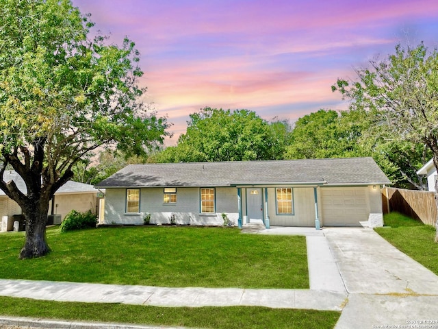 ranch-style house with a garage, a yard, and central AC