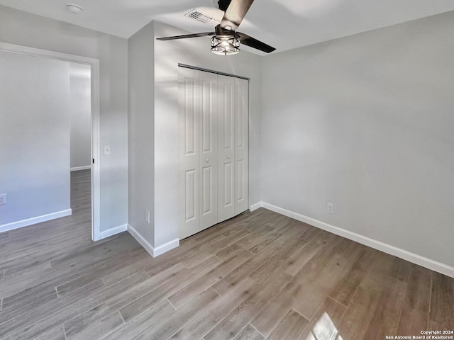 unfurnished bedroom featuring ceiling fan, light hardwood / wood-style floors, and a closet