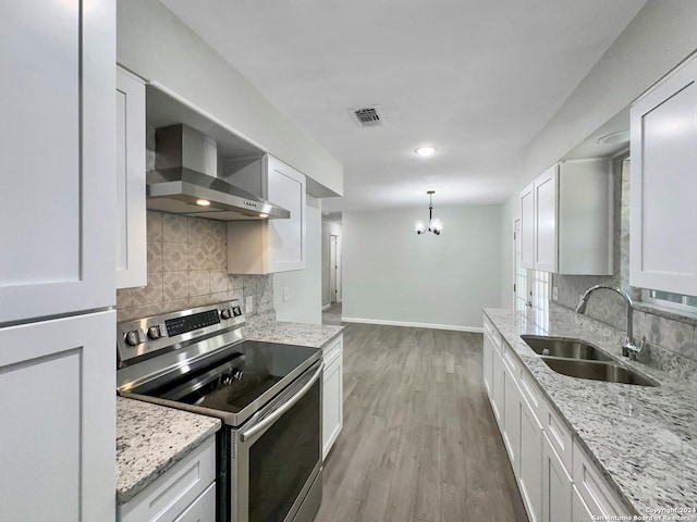 kitchen with wall chimney exhaust hood, white cabinetry, stainless steel electric range oven, and sink