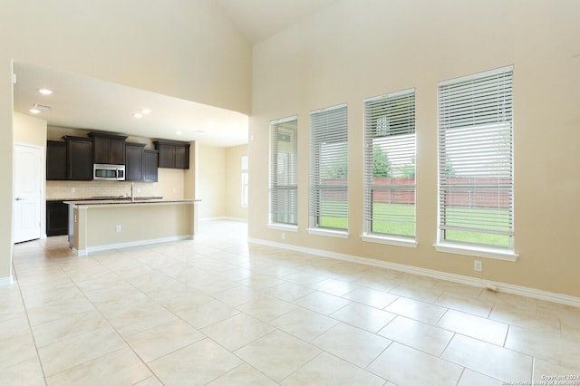 unfurnished living room featuring a towering ceiling and light tile patterned flooring