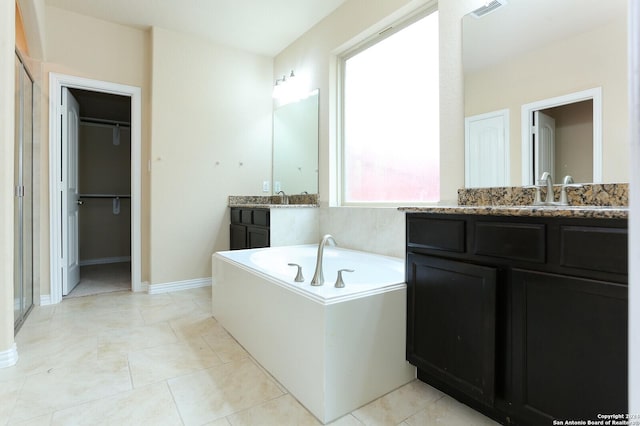 bathroom featuring a tub to relax in, vanity, and tile patterned floors