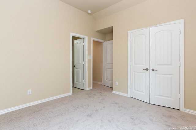 unfurnished bedroom with vaulted ceiling, light colored carpet, and a closet