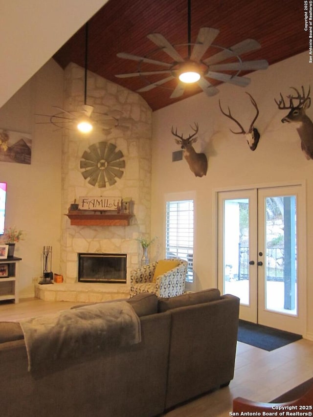 living room featuring high vaulted ceiling, a fireplace, ceiling fan, wood ceiling, and french doors