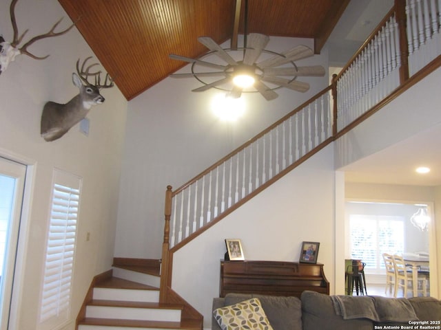 stairway with beamed ceiling, ceiling fan, high vaulted ceiling, and wood ceiling