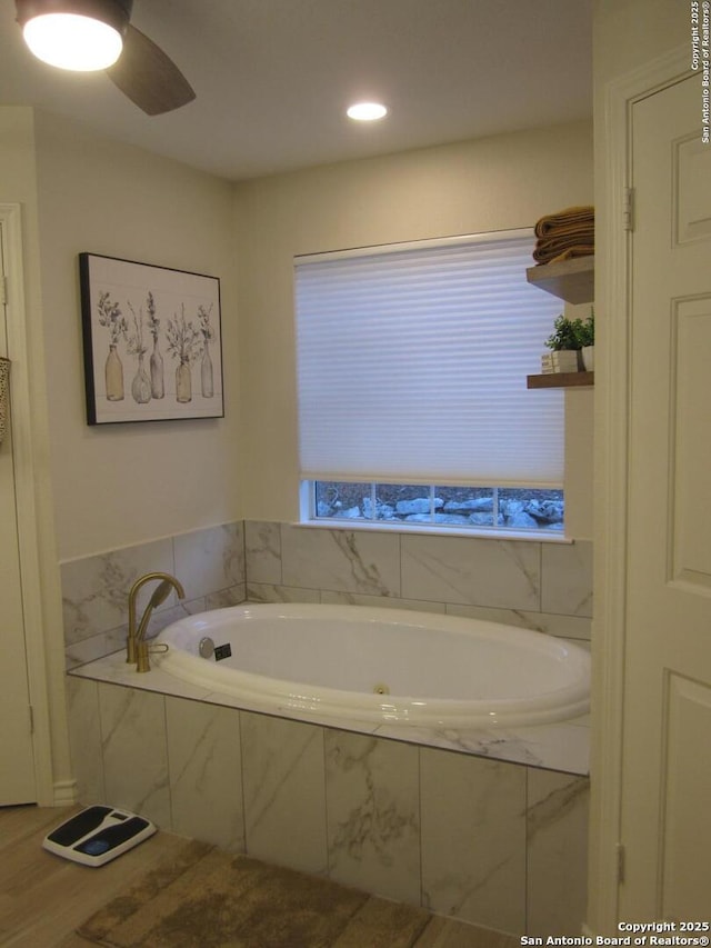 bathroom featuring tiled bath and ceiling fan