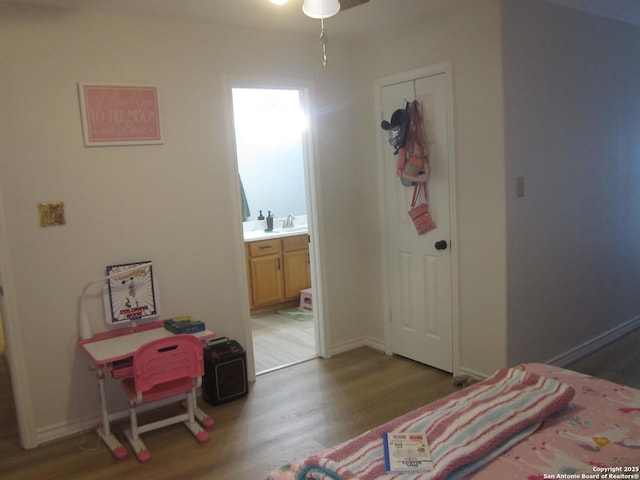 bedroom featuring hardwood / wood-style flooring, ensuite bathroom, and sink