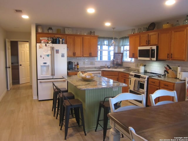 kitchen with a kitchen island, pendant lighting, sink, backsplash, and stainless steel appliances