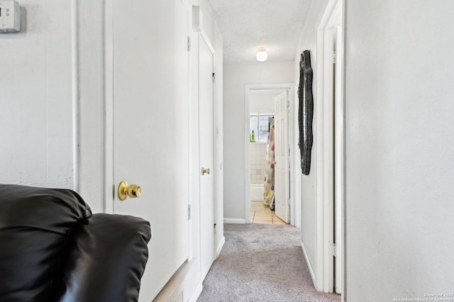 hallway featuring light colored carpet and a textured ceiling