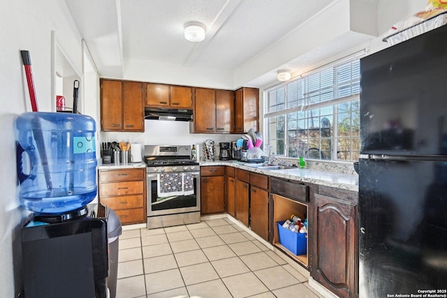 kitchen with gas stove, black fridge, sink, and light tile patterned floors