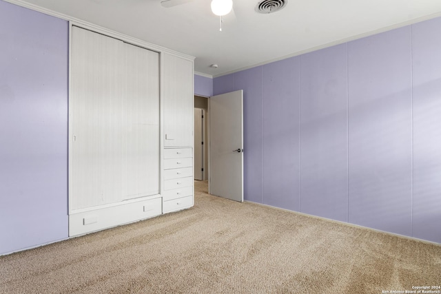 unfurnished bedroom with ceiling fan, ornamental molding, and carpet flooring