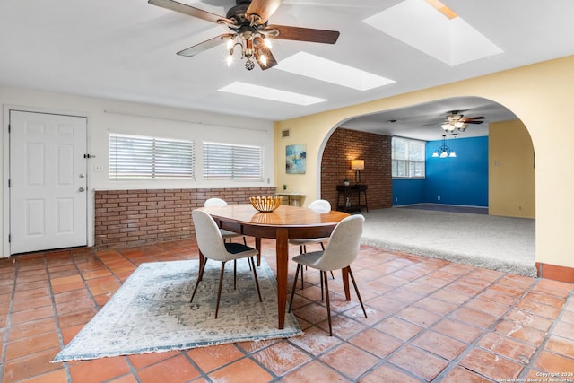 dining area featuring tile patterned flooring, ceiling fan, and brick wall