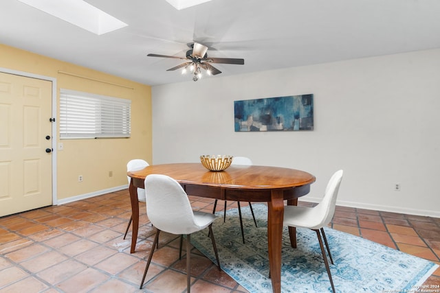 dining area featuring ceiling fan, a skylight, and tile patterned flooring