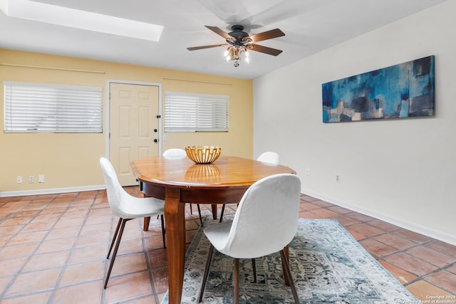 dining room featuring tile patterned flooring, ceiling fan, and a skylight