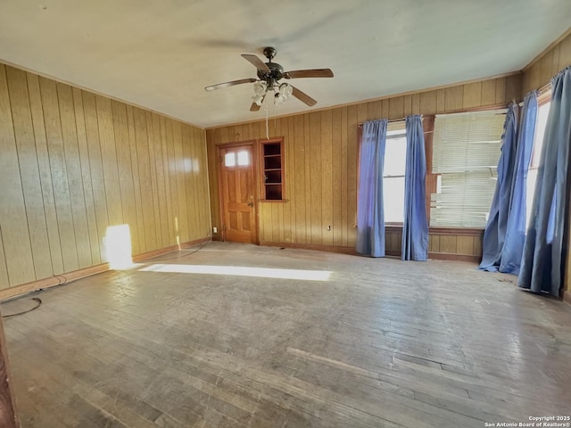 unfurnished room with ceiling fan, wood walls, and light wood-type flooring