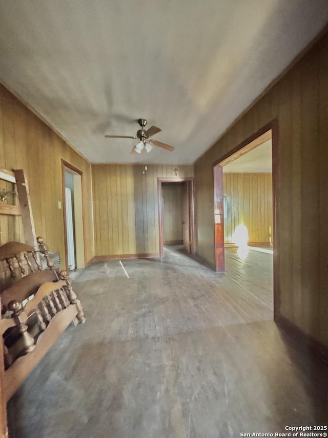 unfurnished living room with wooden walls and ceiling fan