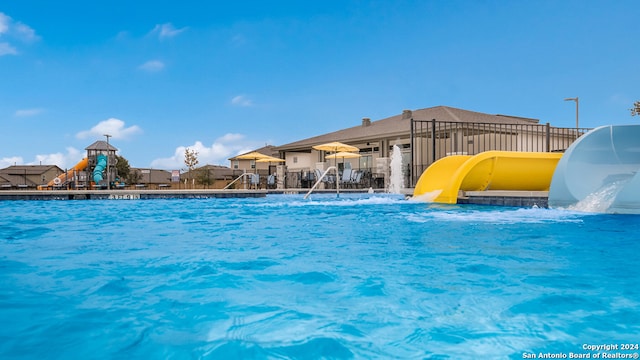 view of swimming pool with a water slide and a playground