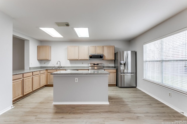 kitchen with appliances with stainless steel finishes, sink, light brown cabinetry, and light hardwood / wood-style floors