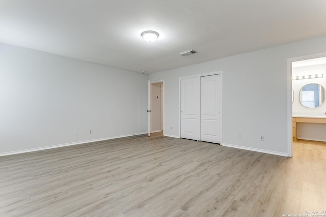 unfurnished bedroom featuring a closet, connected bathroom, and light hardwood / wood-style flooring