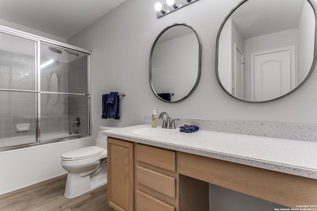 full bathroom with vanity, toilet, hardwood / wood-style floors, and bath / shower combo with glass door