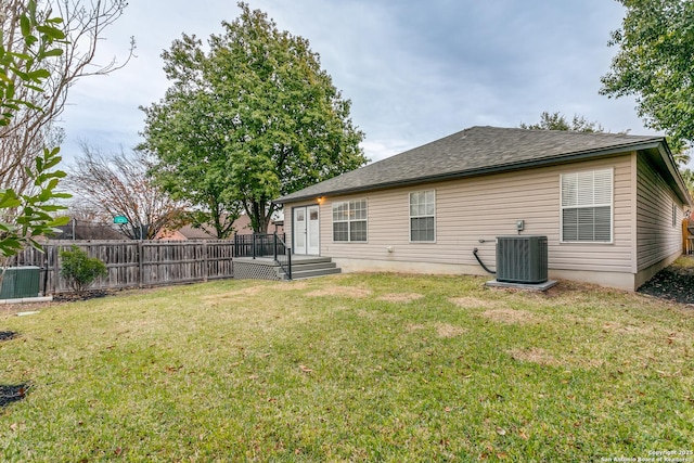 rear view of property featuring central AC and a lawn