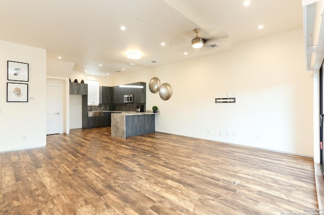 unfurnished living room with light wood-type flooring and ceiling fan