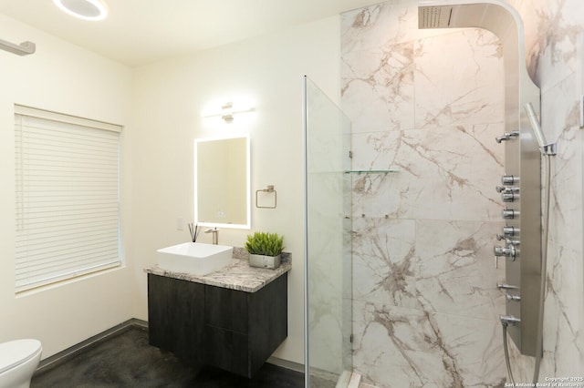 bathroom featuring vanity, tiled shower, and toilet