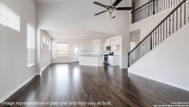 unfurnished living room with a towering ceiling, dark hardwood / wood-style floors, and ceiling fan