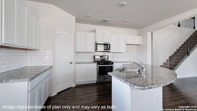 kitchen featuring stainless steel appliances, white cabinetry, sink, and a kitchen island with sink