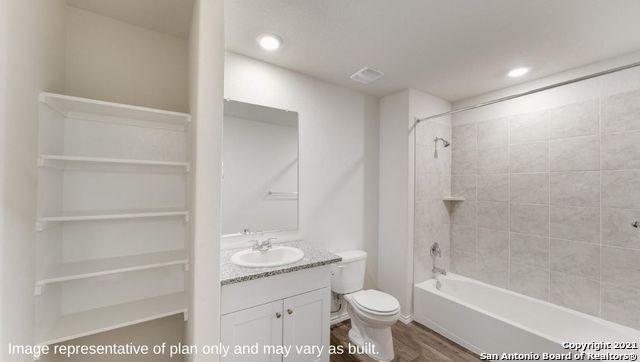 full bathroom with tiled shower / bath, vanity, toilet, and wood-type flooring