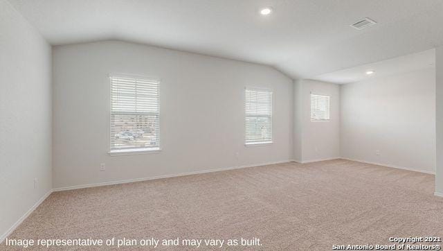 carpeted empty room with lofted ceiling