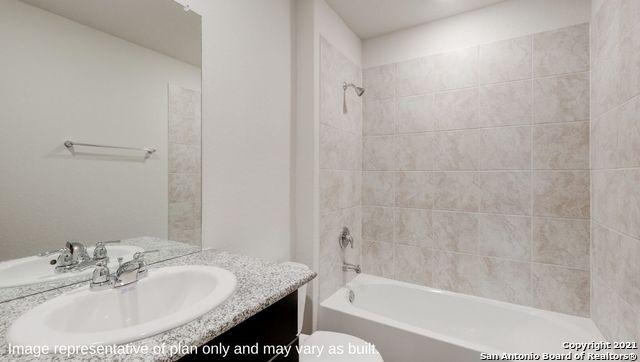 full bathroom with tiled shower / bath, vanity, and toilet