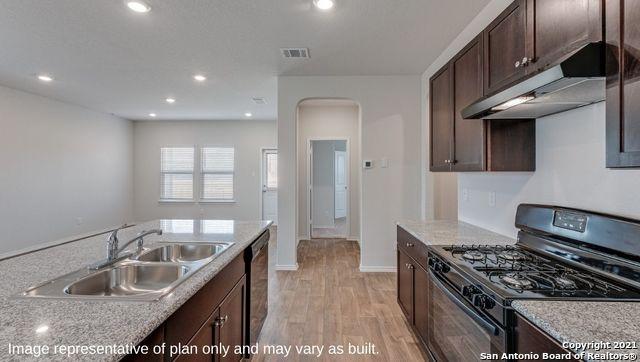 kitchen with dishwasher, sink, light stone counters, and black range with gas cooktop