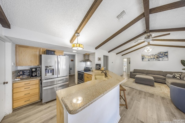 kitchen featuring appliances with stainless steel finishes, sink, hanging light fixtures, wall chimney range hood, and light wood-type flooring