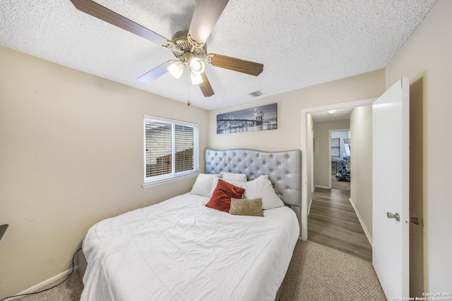 bedroom with ceiling fan, hardwood / wood-style floors, and a textured ceiling