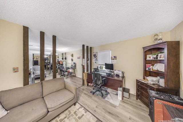 home office with light hardwood / wood-style flooring and a textured ceiling