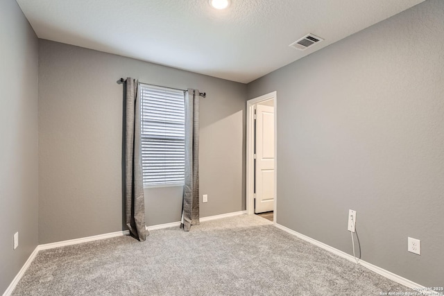 spare room with light colored carpet and a textured ceiling