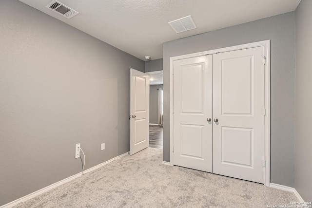 unfurnished bedroom featuring light colored carpet and a closet