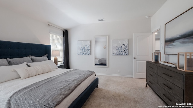 bedroom with vaulted ceiling and light colored carpet