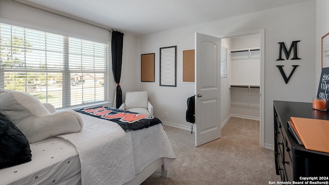 bedroom with light carpet, a walk in closet, and a closet