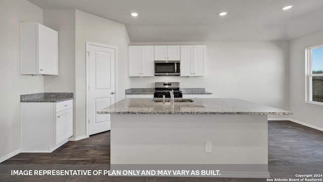 kitchen featuring dark hardwood / wood-style floors, white cabinetry, stainless steel appliances, light stone countertops, and a center island with sink